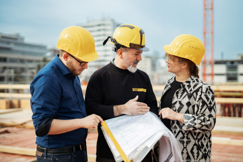 Drei Mitarbeiter beraten sich auf einer Baustelle