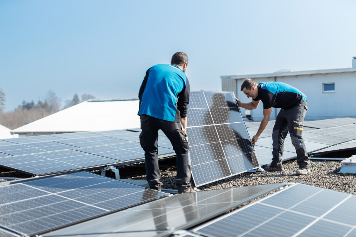 Zwei Mitarbeiter bei der Installation eines Photovoltaikmoduls